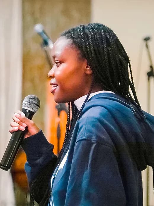 A woman holding a microphone, ready to sing, in an indoor setting.