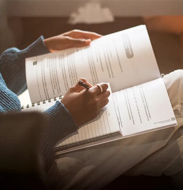 Close-up of a person writing in a recovery programme workbook.