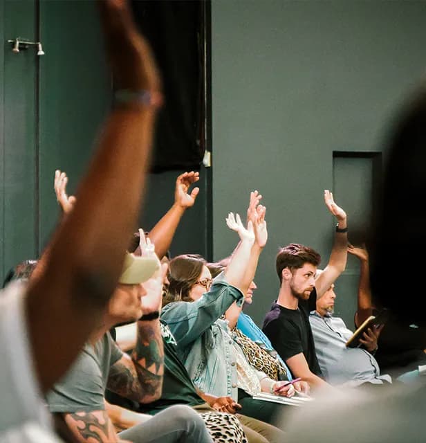 A group of people sitting together with raised hands during a recovery session.