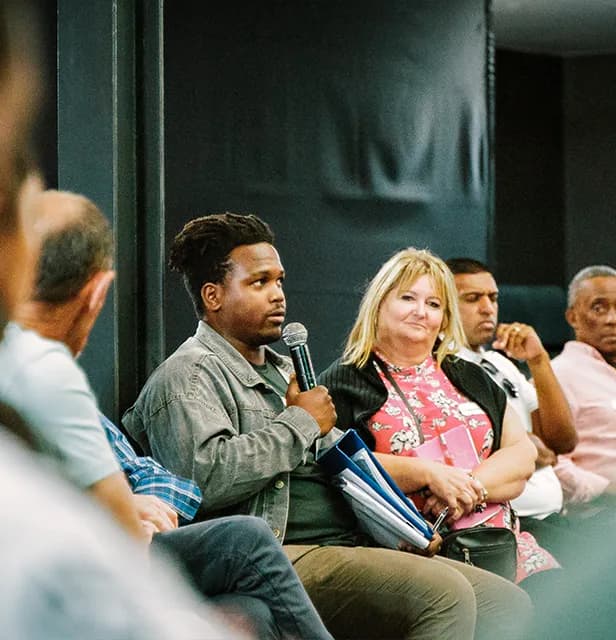 A person speaking into a microphone, sharing at a recovery group.