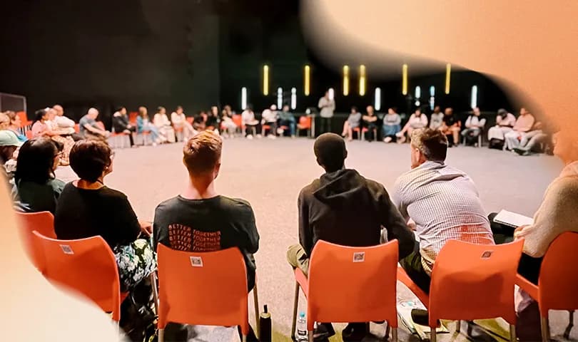 People sitting together in a circle at a recovery group meeting.